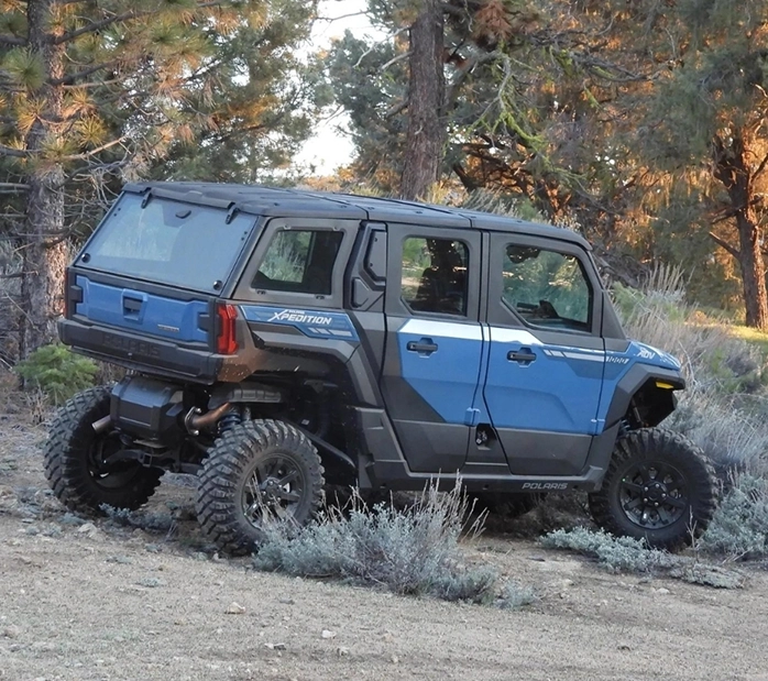 A blue and black vehicle is parked in the dirt.