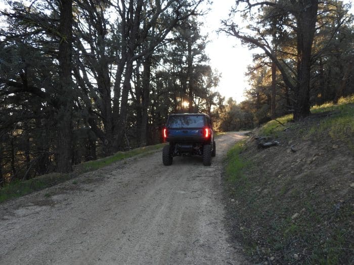 A truck driving down the road in the woods.