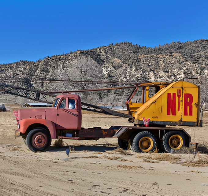 A large truck is parked in the sand.